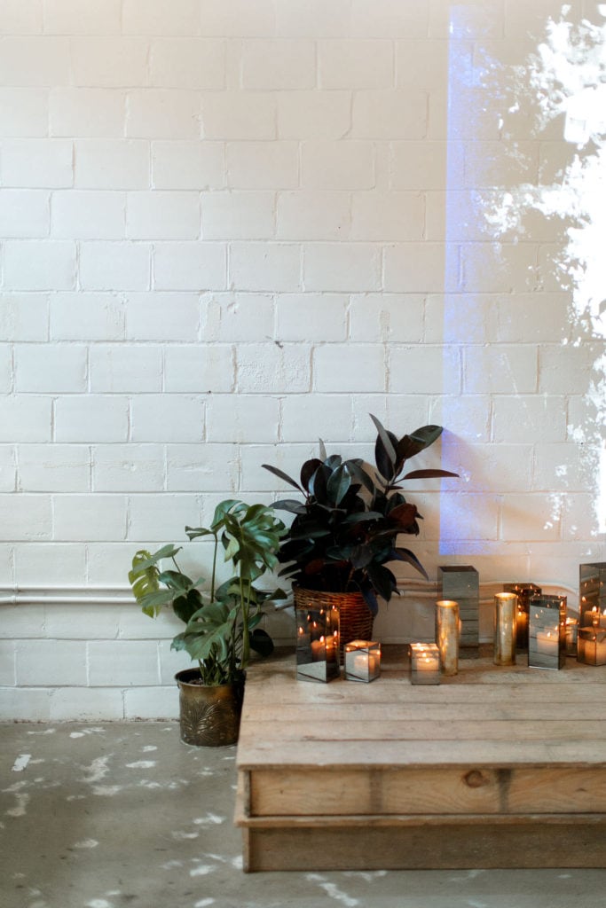 A wedding ceremony stage has houseplants all around, adding to the white and greenery wedding theme.
