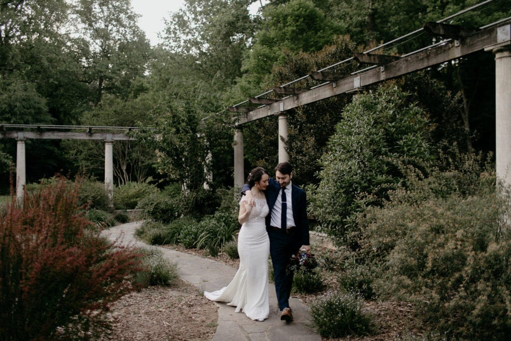 A couple walking through their Atlanta wedding venue Cator Woolford Gardens on their wedding day. A couple walking through their Atlanta wedding venue Cator Woolford Gardens on their wedding day.