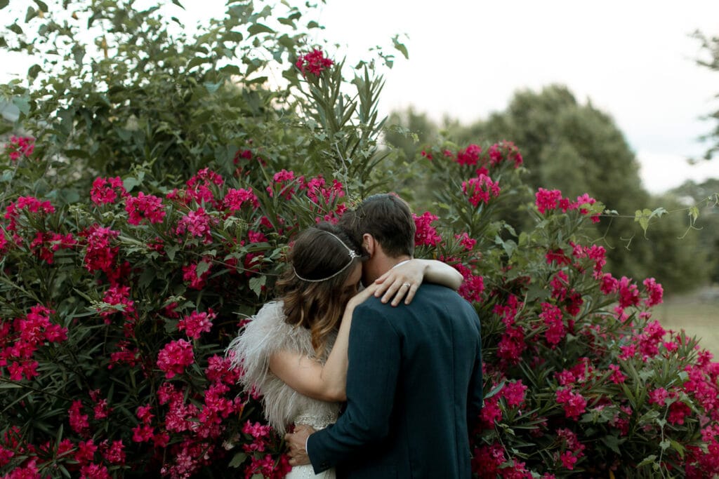 A bride and a groom in a flower bush for their Oakland Cemetery wedding photos. 