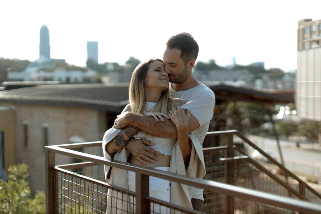 A couple candidly embracing with buildings in the background at The Roof at Ponce City Market in Atlanta.